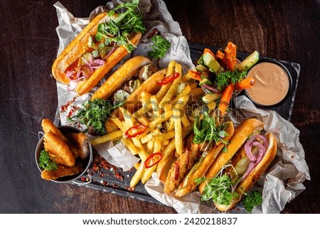 fast food set on plate. hot dog,  burger, potato chips, french fries, vegetables, hashbrown and more on table