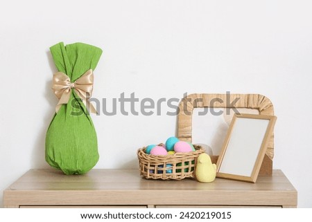 Frames with Easter eggs on commode near light wall