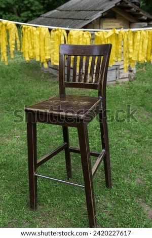 a heavy beautiful wooden brown chair with a high back and a soft cover stands on the green grass during the day on the street