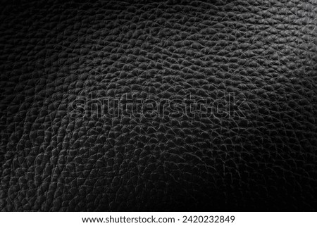 Black leather texture with a dark gradient and light in the center. Leather background