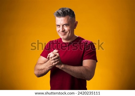 Portrait of smiling man rubbing hands over yellow background. Success and optimistic concept Royalty-Free Stock Photo #2420235111