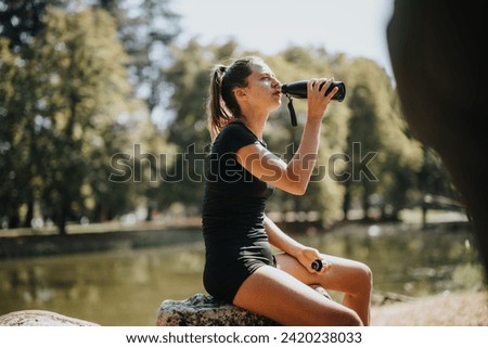 Side view photo of gorgeous girl drinking water while taking a break from workout in the park.