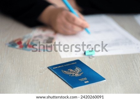 Indonesia passport and service workers table on process of citizenship registration. Female worker fills papers of citizenship Royalty-Free Stock Photo #2420260091