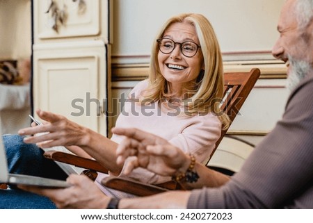 Cheerful senior caucasian couple spouses husband and wife talking while sitting in deck chairs near their van camper home trailer home on wheels. Away from everything concept Royalty-Free Stock Photo #2420272023