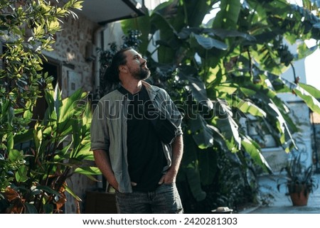Portrait of a male tourist on a picturesque street of the old town.  A young, handsome guy in a light shirt walks through the green, narrow streets of the ancient city center Royalty-Free Stock Photo #2420281303