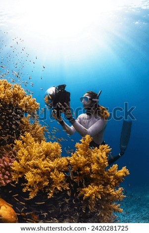 A woman is taking a picture of a coral reef,What a wonderful scene.