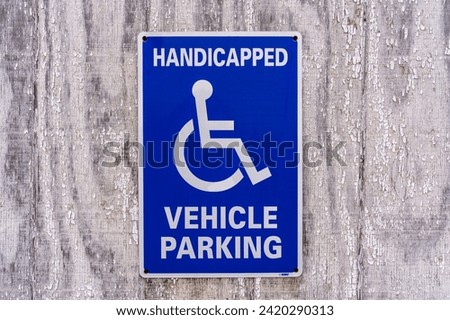 Blue sign reading Handicapped Vehicle Parking with iconic wheelchair sign