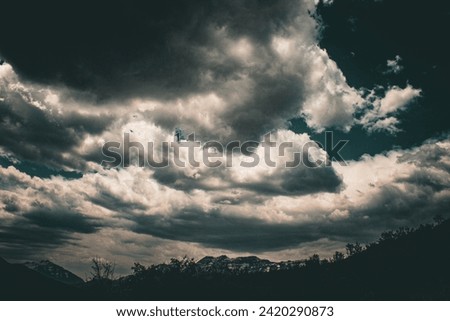 beautiful moody intense cloudscape with snowy mountain landscape dark skies nature photography