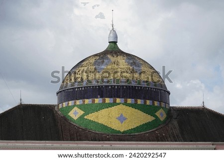 Dome of the Amazonas Theater with coloured tiles placed as the flag of Brazil. It is the famous landmark of Manaus, the capital of the state of Amazonas. It was built until 1896 during the rubber era. Royalty-Free Stock Photo #2420292547