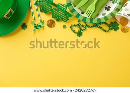 Majestic clover fest: St. Paddy's Day soirée. Top view of paper plates, cutlery, cups, straws, leprechaun hat, trefoils, coins, party eyewear, beads on yellow background with well-wishing space