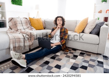 Full length photo of uncertain unsure guy dressed checkered shirt texting modern gadget indoors house home room Royalty-Free Stock Photo #2420294581