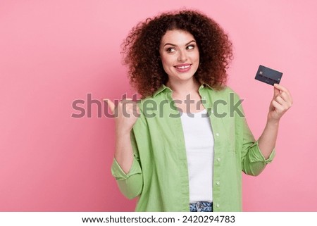 Photo portrait of lovely young lady hold credit card point look empty space wear trendy green garment isolated on pink color background