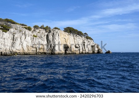 Unique white rocks with caves above the sea surface in the National Park of Calanques in France. View from the sea.