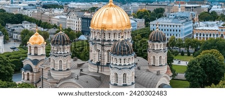 The Nativity of Christ Cathedral in Riga, Latvia. Byzantine-styled Orthodox cathedral, the largest in the Baltic region, with golden colored dome, polished gilded cupolas gleaming through the trees Royalty-Free Stock Photo #2420302483