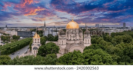 The Nativity of Christ Cathedral in Riga, Latvia. Byzantine-styled Orthodox cathedral, the largest in the Baltic region, with golden colored dome, polished gilded cupolas gleaming through the trees Royalty-Free Stock Photo #2420302563
