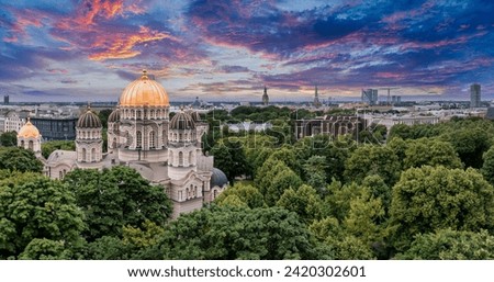 The Nativity of Christ Cathedral in Riga, Latvia. Byzantine-styled Orthodox cathedral, the largest in the Baltic region, with golden colored dome, polished gilded cupolas gleaming through the trees Royalty-Free Stock Photo #2420302601