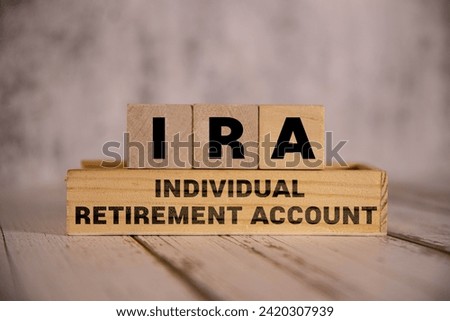 On a bright blue background, light wooden blocks and cubes with the text IRA Individual Retirement Account. Royalty-Free Stock Photo #2420307939