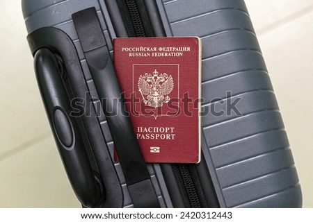 Closeup view of russian passport and grey suitcase.