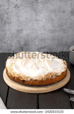 Meringue cake with rhubarb on a brown table. Vertical photo