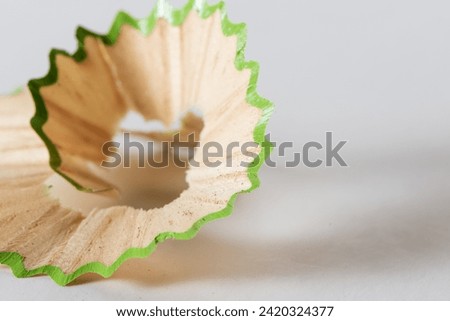 Macro photo of a wood colored pencil shaving over a textured background.