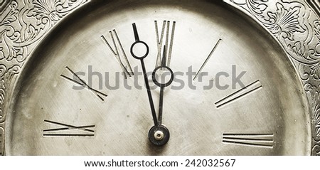 Old silver clock with roman numbers indicating it's about time. Royalty-Free Stock Photo #242032567