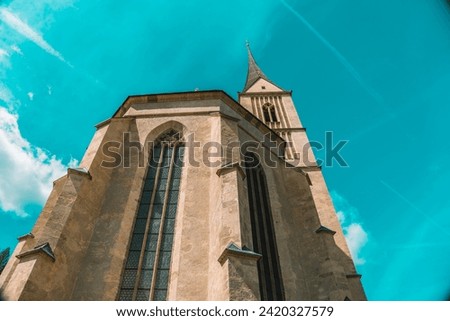 Church of St. Leonard in Austria on a bright blue sky background. Bottom view . Catholic Church architecture outside.Church building in Gothic style.Christian and catholic faith symbol.Religious