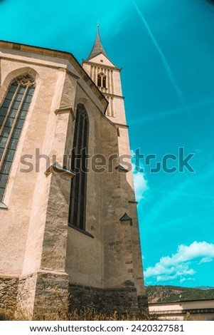 Church of St. Leonard in Austria on a bright blue sky background. Catholic Church architecture outside.Church building in Gothic style.Christian and catholic faith symbol.Religious symbol.