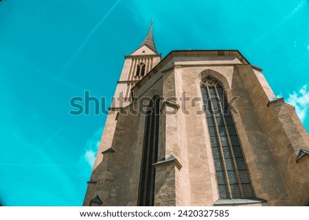 Church of St. Leonard in Austria on a blue sky background. Bottom view . Catholic Church architecture outside.Church building in Gothic style.Christian and catholic faith symbol.Religious symbol.