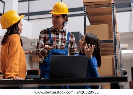 Postal service workers arguing about delivery checklist while analyzing data on laptop in warehouse. Asian man and women storehouse employees team discussing goods logistics Royalty-Free Stock Photo #2420328955