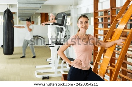 Young caucasian woman standing at gym ladder and looking at camera.