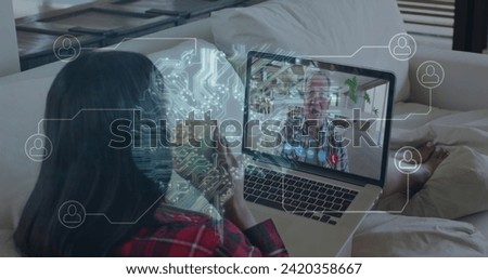 Image of glowing computer motherboard with network of icons over woman on image call with laptop. Digital interface global connection and communication concept digitally generated image.