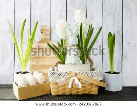 Decorative Easter composition on a wooden background wicker basket with spring flowers hyacinths decorated with a rabbit, Easter eggs, decorations for the kitchen, home. Front view.

