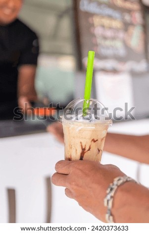 Focus on a frappe in hands of a customer while paying