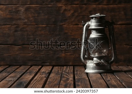 Kerosene lantern lamp on the old wooden desk table background with copy space. Front view.