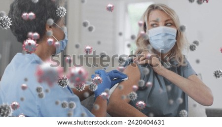 Image of covid 19 cells over woman receiving vaccination wearing face mask. global covid 19 pandemic, health and medicine concept digitally generated image.