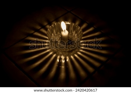 A burning candle in a glass bowl casts a beautiful glow on the floor