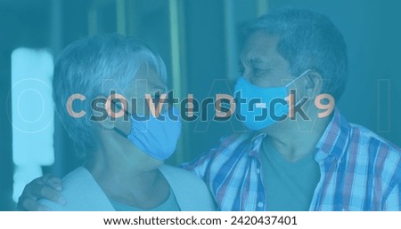 Image of covid 19 text over senior couple embracing wearing face masks. global covid 19 pandemic, health and medicine concept digitally generated image.