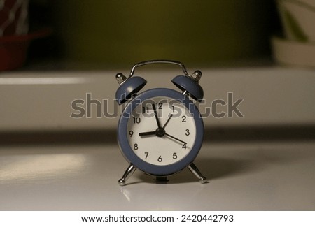 A small, elegant timepiece gracing the scene with its timeless charm. This diminutive clock, adorned with delicate details, radiates a classic aesthetic. Royalty-Free Stock Photo #2420442793