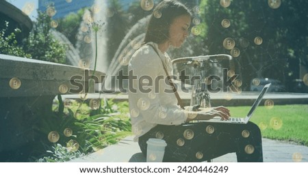 Image of bitcoin icons over woman using laptop in park. global technology, finance and business concept digitally generated image.