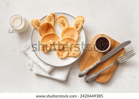 Funny Easter bunny pancakes with milk and jam on white background