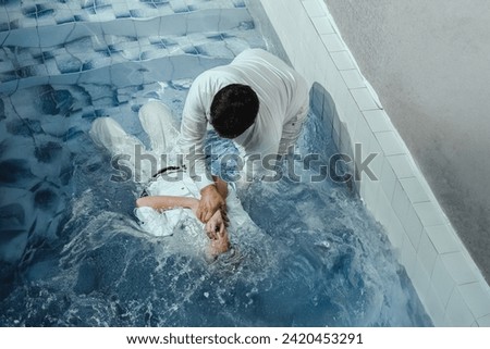 A Protestant pastor baptizes a man in water in the name of Jesus Christ Royalty-Free Stock Photo #2420453291