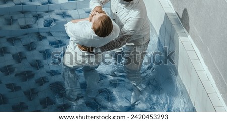 A Protestant pastor baptizes a man in water in the name of Jesus Christ Royalty-Free Stock Photo #2420453293