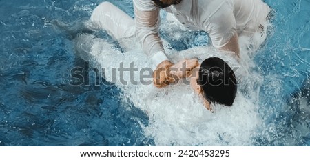 A Protestant pastor baptizes a man in water in the name of Jesus Christ Royalty-Free Stock Photo #2420453295