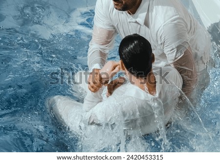 A Protestant pastor baptizes a man in water in the name of Jesus Christ Royalty-Free Stock Photo #2420453315