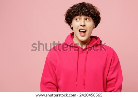 Young shocked amazed surprised Caucasian man he wears hoody casual clothes look aside on area with opened mouth isolated on plain pastel light pink color background studio portrait. Lifestyle concept