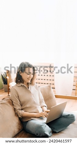 Vivacious Woman in the Living Room. Typing on Laptop with Energy A vivacious woman is typing on a laptop, sitting on the sofa in the living room. Sofa Workstation. Energetic Woman Typing on Her Laptop Royalty-Free Stock Photo #2420461597