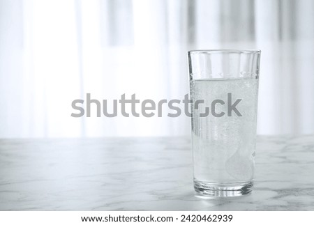 Glass of water with effervescent tablet on marble table indoors, space for text