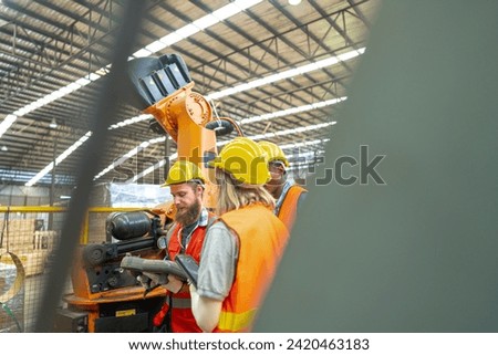 team Engineers standing by robotic arm and operating machine in factory. worker man control on tablet. Workers work at heavy machine robot arm. High-tech robot with a remote system in Wood factory.