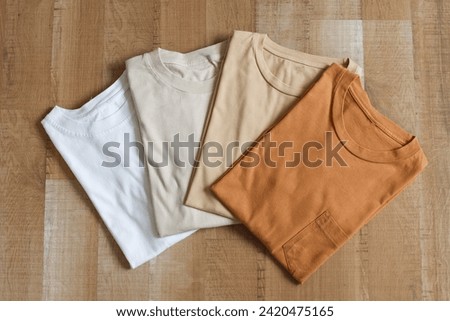 Collection of brown colors variant t-shirt folded on wooden floor  Royalty-Free Stock Photo #2420475165