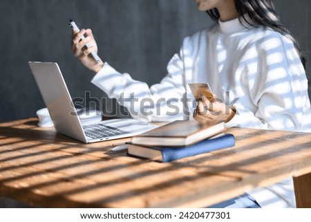 Woman in white shirt holding debit card and smartphone